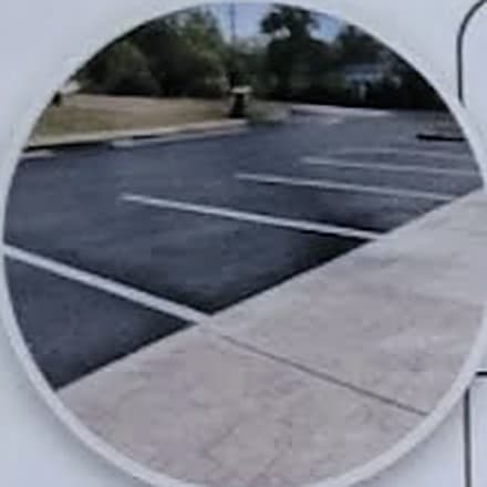 A freshly cleared and marked parking lot beside a clean concrete walkway
