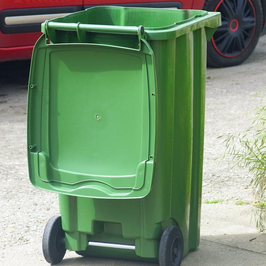A wheeled refuse bin standing on a driveway, ready to be taken out
